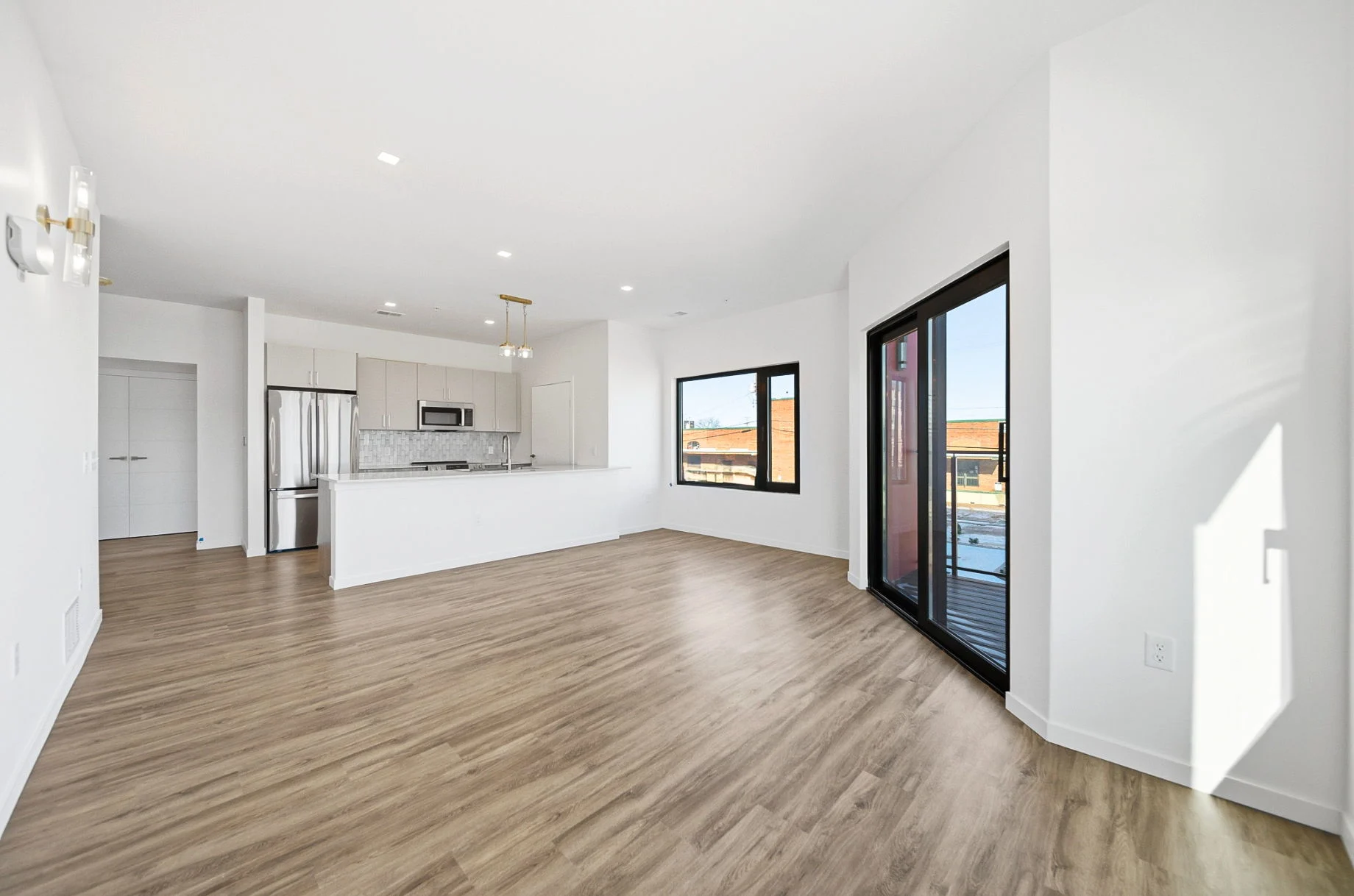 Bright living room with an island kitchen, stainless steel appliances and a balcony door in a downtown Dayton apartment